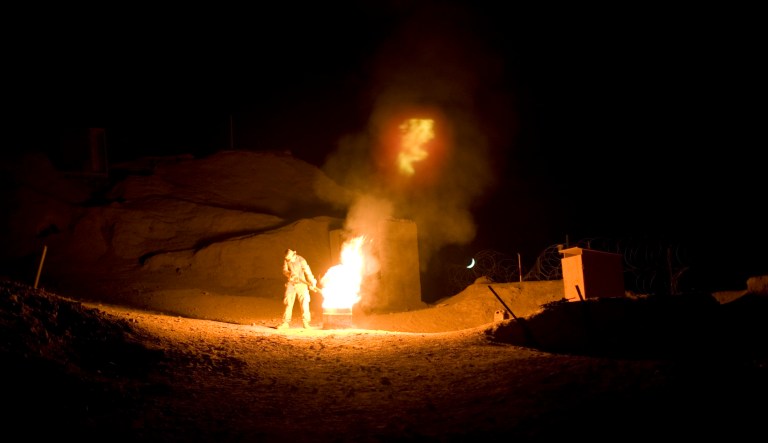 In this photo taken on Monday, Oct. 11, 2010, U.S. Army soldier Spc. Shaea Koyj, from New Jersey, burns a tub of excrement at an outpost in Zhari district, Kandahar province.