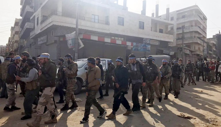 Turkey-backed Free Syrian Army soldiers walk in city center of Afrin, northwestern Syria, early Sunday, March 18, 2018. Turkey's President Recep Tayyip Erdogan said Sunday that allied Syrian forces have taken "total" control of the town center of Afrin, the target of a nearly two-month-old Turkish offensive against a Syrian Kurdish militia, which said fighting was still underway. Erdogan said the Turkish flag and the flag of the Syrian opposition fighters have been raised in the town, previously controlled by the Kurdish militia known as the People's Defense Units, or YPG.