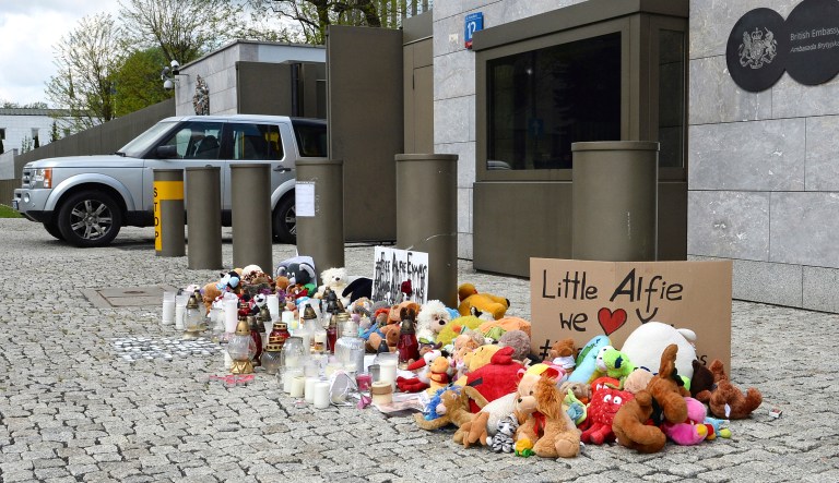 A car drives past flowers and other tributes for terminally ill British toddler Alfie Evans placed outside the British Embassy in Warsaw, Poland, Thursday, April 26, 2018. The sick child's plight has elicited sympathy in mostly Catholic Poland, where even President Andrzej Duda has said the child "must be saved." Duda's words were seen as implicit criticism of the British health system, which took the child off life support this week.