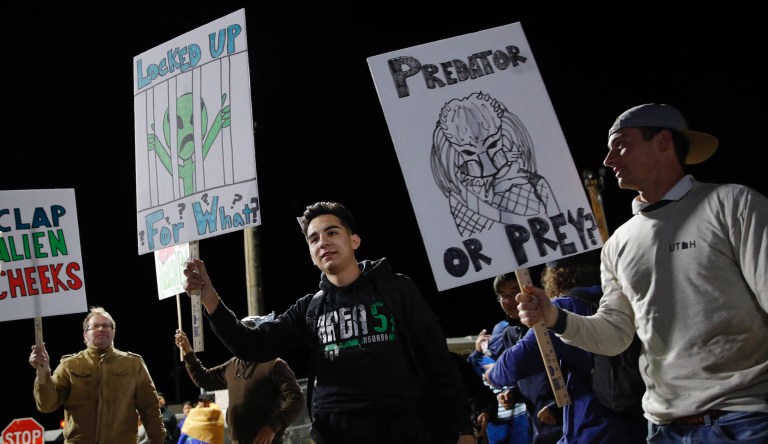 People holds signs at an entrance to the Nevada Test and Training Range near Area 51 Friday, Sept. 20, 2019, near Rachel, Nev. People gathered at the gate inspired by the "Storm Area 51" internet hoax.