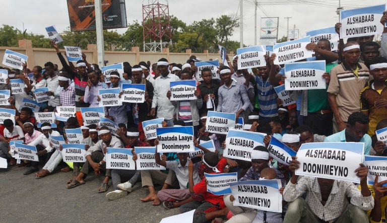 Mourners carry banners which read "Black day" and "Down with Al shabab" during the anniversary an explosion in the capital of Mogadishu, Somalia, Sunday Oct. 14, 2018.