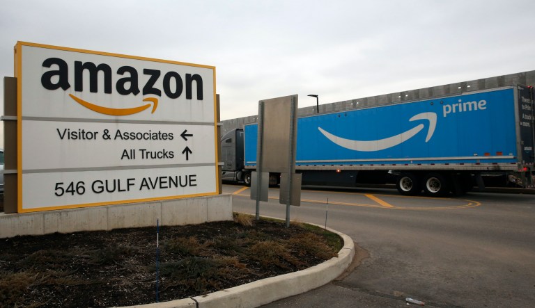 An Amazon Prime truck passes by the sign outisde an Amazon fulfillment center, Thursday, March 19, 2020, in Staten Island, New York. The company's plans to add fulfillment and distribution center positions to keep up with increased demand during the coronavirus outbreak.