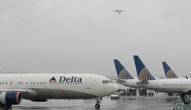 A Delta Airlines jet taxis past United Airlines planes parked on the tarmac Monday, June 9, 2008, at Seattle Tacoma International Airport. 