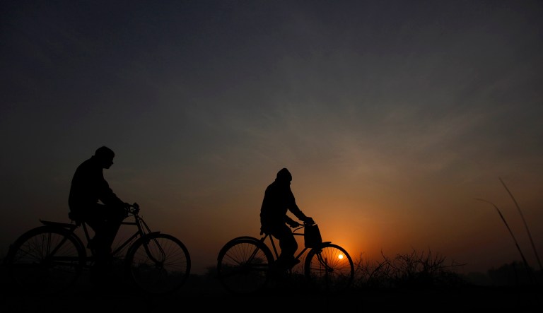 Villagers cycle to work at sunrise in Ghaziabad, on the outskirts of New Delhi, India, Saturday, Feb. 6, 2010.