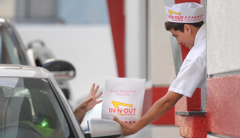 A customer reaches for his order from the drive-through at In-N-Out Burger in the Hollywood area of Los Angeles.