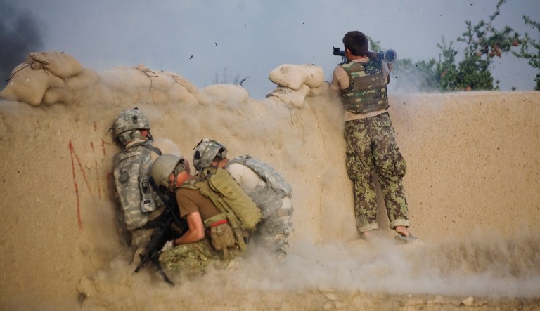 An Afghan soldier launches a rocket propelled grenade as U.S. soldiers duck during a clash with insurgents in the volatile Arghandab Valley, Kandahar, Afghanistan, Tuesday, July 27, 2010. 