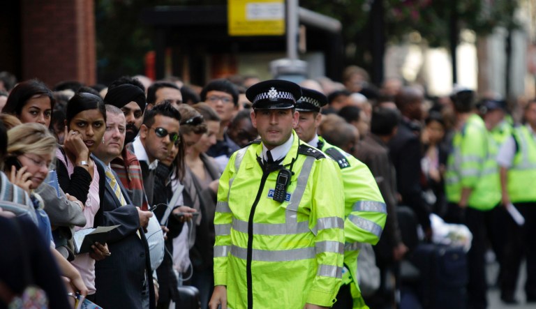 British police officers try to control the crowds as commuters wait at a bus stop in central London, Tuesday, Sept. 7, 2010. 