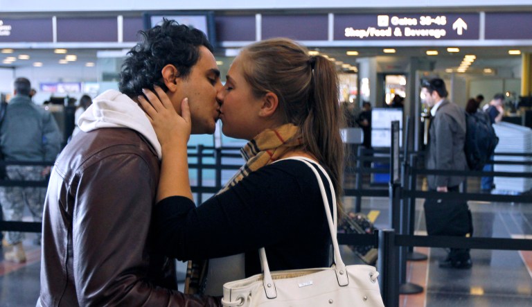 Kivanc Dalgic (left) and Lauren Keeney (right) share a kiss before Keeney goes through the TSA security checkpoint at Washington's Ronald Reagan Washington National Airport.