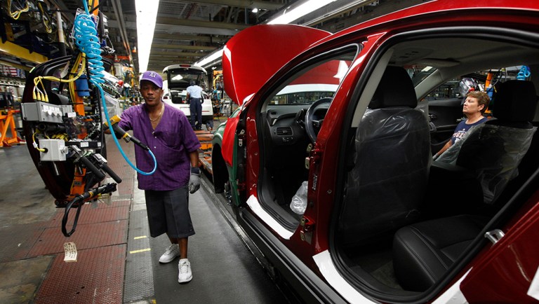 Assembly line worker Edward Houie moves a door into position for a 2012 Chevrolet Volt at the General Motors Hamtramck Assembly plant in Hamtramck, Mich.