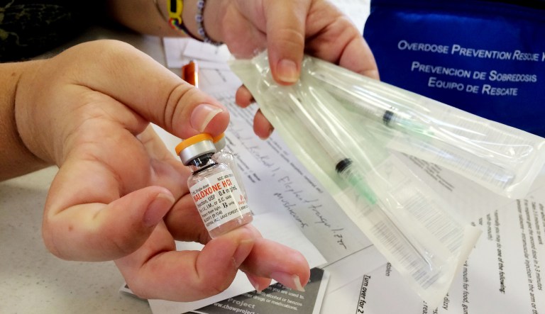 Stacy Lenze, a community health outreach worker, holds a vial of naloxone and syringes in Honolulu, Hawaii.