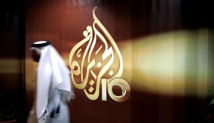 An employee walks past the logo of Al Jazeera in Doha, Qatar.