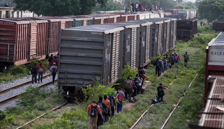 Migrants walk along train tracks and boxcars after getting off a train during their journey toward the US-Mexico border. The migrants pay thousands of dollars per person for the illegal journey across thousands of miles in the care of smuggling networks that in turn pay off government officials, gangs operating on trains and drug cartels controlling the routes north.