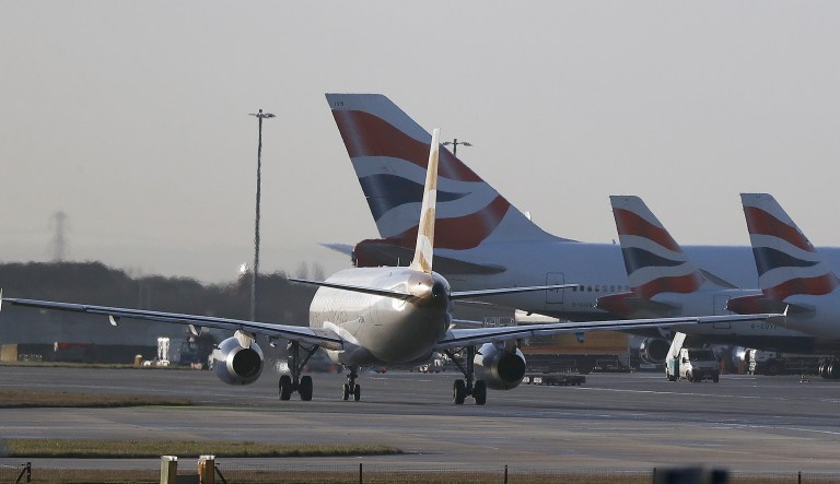 A plane passes other British Airways planes waiting at Heathrow Airport during a 48-hour cabin crew strike in London, Tuesday, Jan. 10, 2017.