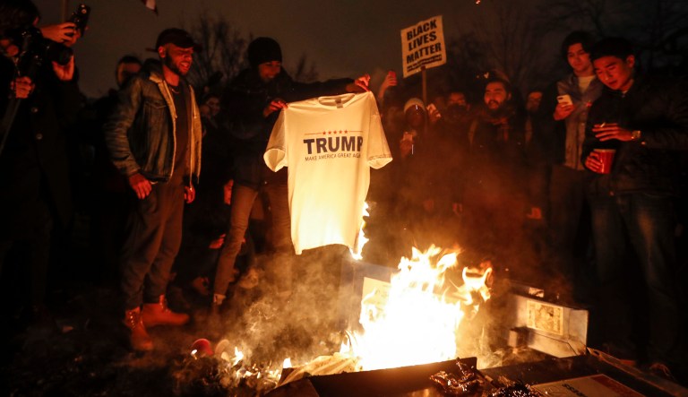 A protester burns a "Make America Great Again" t-shirt during a demonstration in Washington, Friday, Jan. 20, 2017, after the inauguration of President Donald Trump.