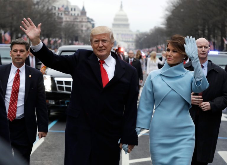 President Donald Trump waves as he walks with first lady Melania Trump during the inauguration parade on Pennsylvania Avenue in Washington, Friday, Jan. 20, 2016. 
