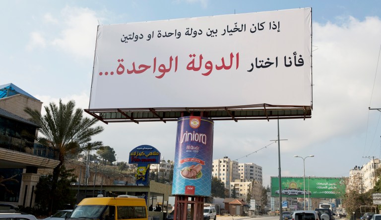 Motorists pass a banner supporting the creation of a single state for Israelis and Palestinians which reads in Arabic: "If I had to choose between one state and two states, I would choose the one state," in the West Bank city of Ramallah, Thursday, Feb. 23, 2017.
