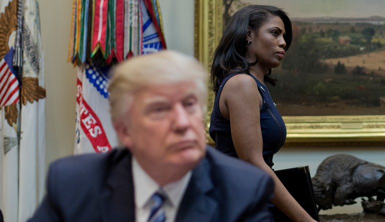 Former White House aide Omarosa Manigault walks past President Trump during a meeting in the White House. 