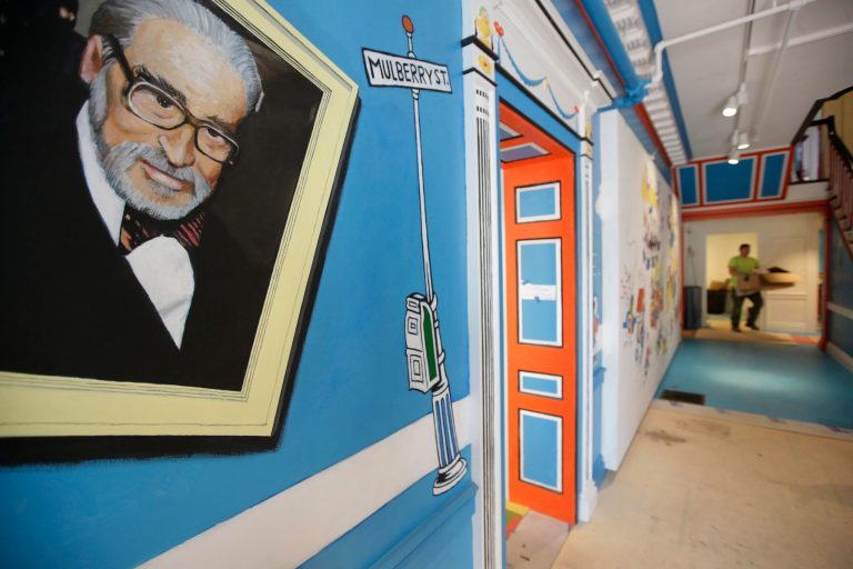 In this May 4, 2017, photo a mural that features Theodor Seuss Geisel, left, also know by his pen name Dr. Seuss, rests on a wall near an entrance at The Amazing World of Dr. Seuss Museum, in Springfield, Mass. 