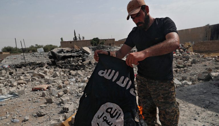 A fighter of the Christian Syriac militia that battles Islamic State militants under the banner of the U.S.-backed Syrian Democratic Forces, burns an IS flag on the front line on the western side of Raqqa, northeast Syria, Monday, July 17, 2017. 