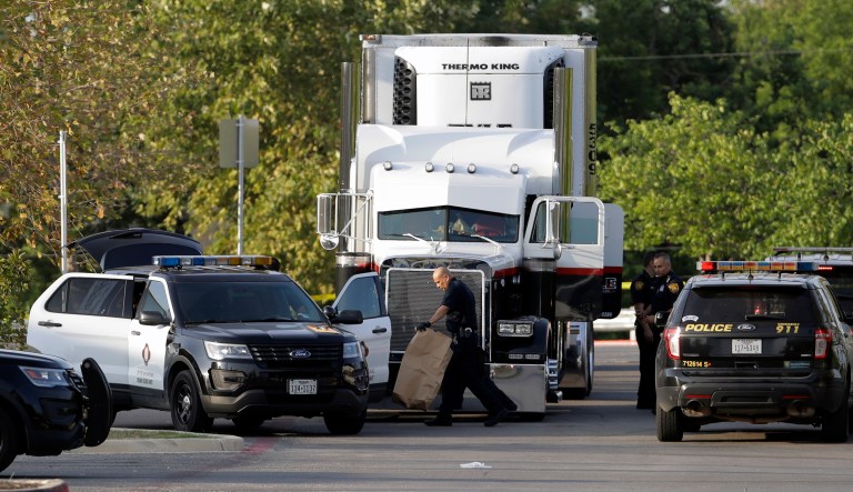San Antonio police officers investigate the scene where eight people were found dead in a tractor-trailer loaded with at least 30 others outside a Walmart store in stifling summer heat in what police are calling a horrific human trafficking case, Sunday, July 23, 2017, in San Antonio.