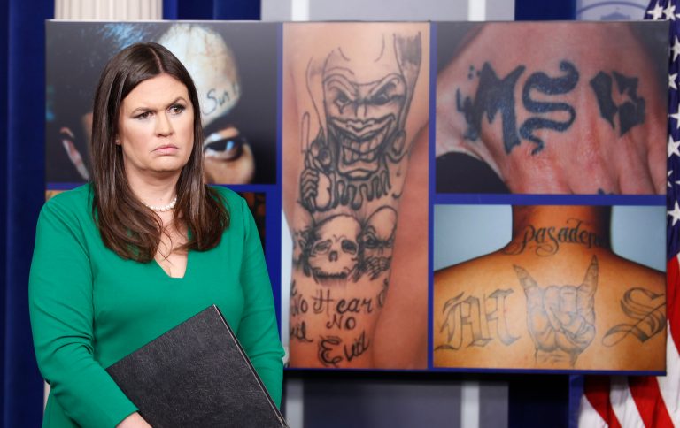 White House press secretary Sarah Huckabee Sanders stands in front of pictures of MS-13 gang tattoos during a press briefing at the White House in Washington, Thursday, July 27, 2017.