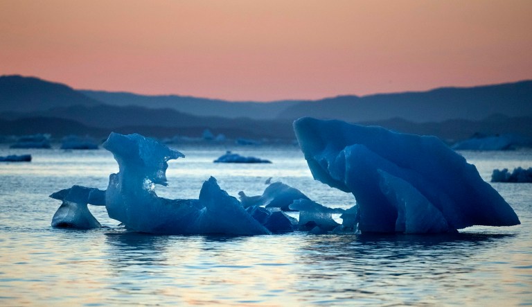 The suns sets as an iceberg floats in the Nuup Kangerlua Fjord near Nuuk in southwestern Greenland.