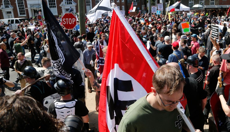 A white supremacist carries a Nazi flag into the entrance to Emancipation Park in Charlottesville, Va., on Aug. 12, 2017.
