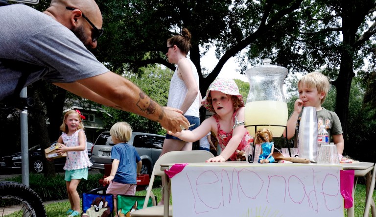 Catherine Grace Avent, 5, hands a cup of lemonade to a customer as Waylon Beck, right, also 5, looks on in Houston.