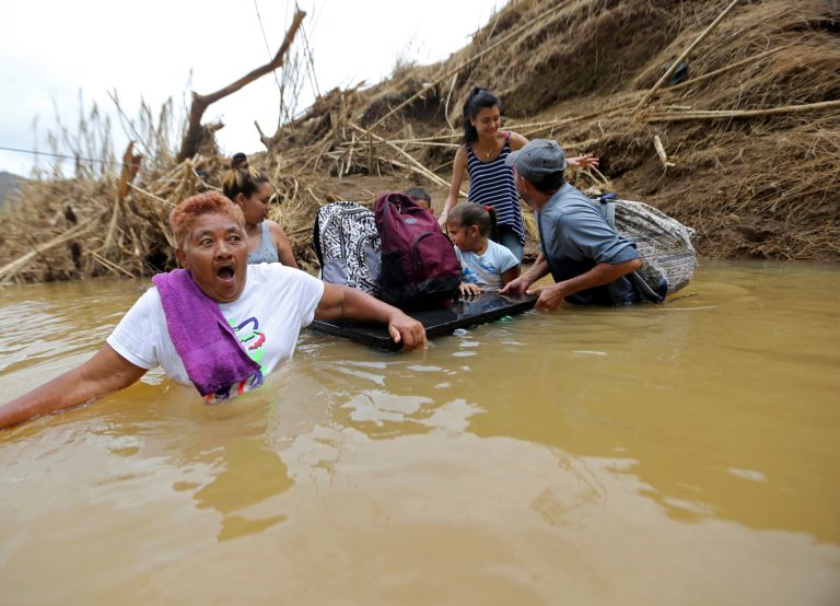 Marta Sostre Vazquez reacts as she starts to wade into the San Lorenzo Morovis River with her family in Morovis, Puerto Rico, Wednesday, Sept. 27, 2017, after a bridge was swept away by Hurricane Maria. The family was returning to their home after visiting family on the other side. (AP Photo/Gerald Herbert)