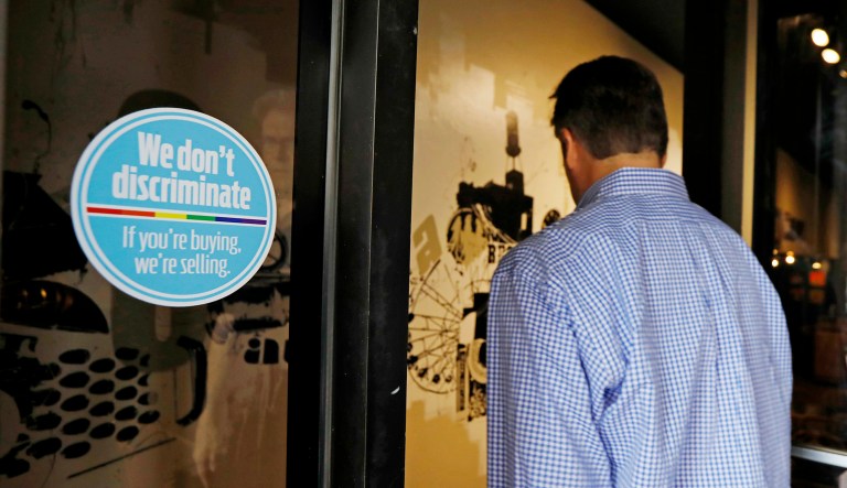 A customer walks into a restaurant that displays a sticker against LGBT discrimination in the doorway.