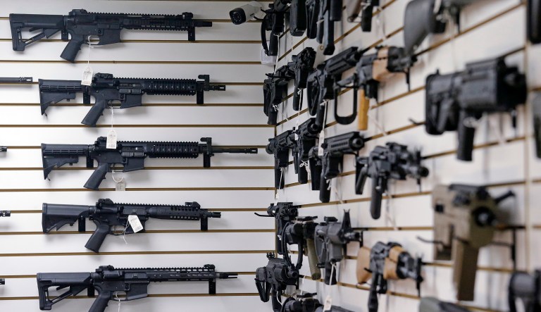Dozens of semi-automatic rifles line a pair of walls in a gun shop. 