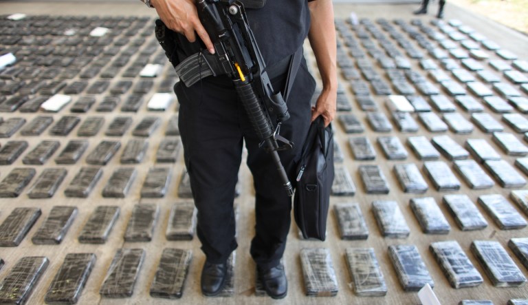 FILE - In this March 16, 2013 file photo, an officer of the Prosecutor General's Office guards packages containing cocaine during a media presentation at the airport in Tumaco, Colombia. A year after the peace accords between the Colombian government and the Revolutionary Armed Forces of Colombia, FARC, in 2016, the city is disputed among criminal gangs and a dissident FARC movement, all of which are recruiting former rebels whose only marketable skill is wielding a gun. 