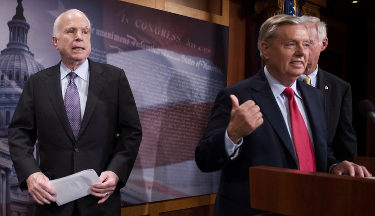 Sen. John McCain, R-Ariz., walks onstage as Sen. Lindsey Graham, R-S.C., points to him while he speaks to reporters at the Capitol on July 27, 2017.