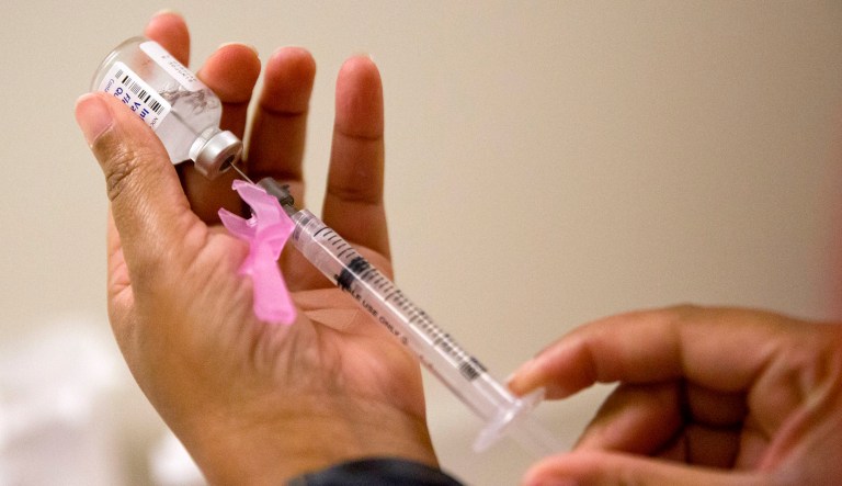A person prepares a flu shot at a clinic.