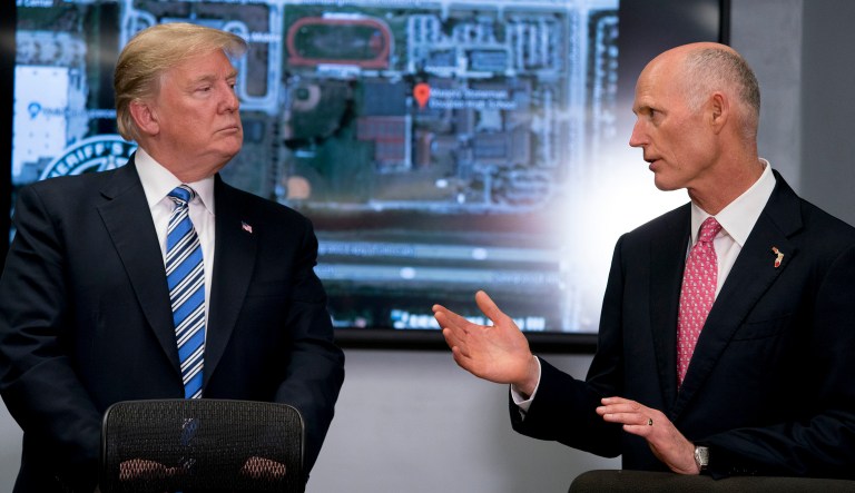 Florida Gov. Rick Scott speaks to President Trump as they meet with law enforcement officers at Broward County Sheriff's Office in Pompano Beach, Fla. following the shooting at Marjory Stoneman Douglas High School, in Parkland, Fla. 