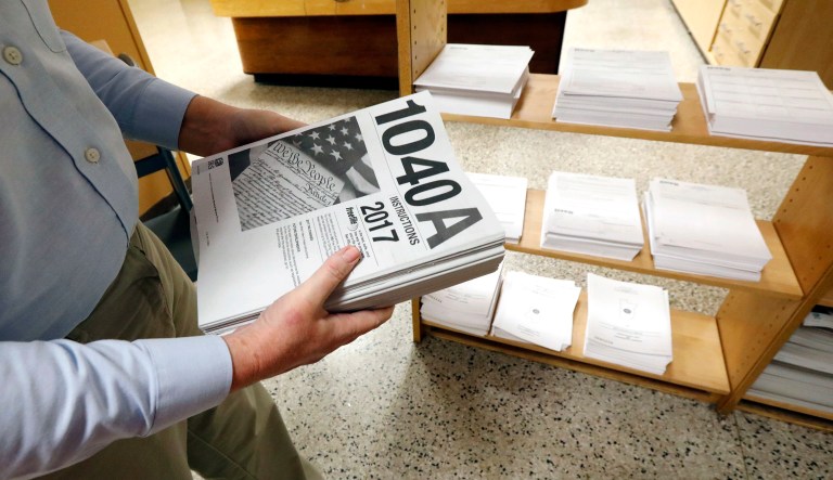 FILE- In this Feb. 15, 2018, photo, Susan Prendergast, reference supervisor at the Eudora Welty Library, in Jackson, Miss., adds additional federal tax filing information booklets on a shelf. The U.S. Treasury Department and the Internal Revenue Service on Wednesday, Feb. 28, 2018, issued an online calculator for figuring whether money is being set aside, to avoid facing a huge tax bill for 2018.