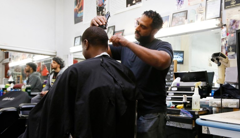 In this Sunday, March 11, 2018, photo, barber Eric Muhammad, owner of A New You Barbershop cuts the hair of customer Marc M. Sims in Inglewood, California.