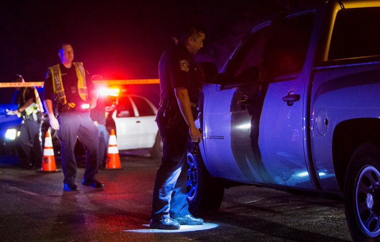 An Austin police officer directs a vehicle away from the scene of an explosion in Austin, Texas, Sunday, March 18, 2018. At least a few people were injured in another explosion in Texas' capital late Sunday, after three package bombs detonated this month in other parts of the city, killing two people and injuring two others. 