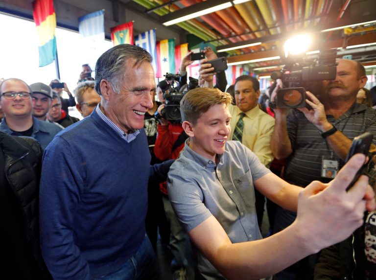 FILE - In this Feb. 16, 2018, file photo, former Republican presidential candidate Mitt Romney, left, poses for a photo as he greets students at Utah Valley Universit, in Orem, Utah. Romney says he's more conservative than President Donald Trump on immigration. Romney, who is seeking a Utah Senate seat held by Republican Orrin Hatch, said at an event in Provo, Utah, Monday, March 26, 2018, that he is "probably more of a hawk on immigration than even the President."