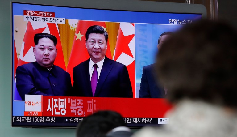 People watch a news program on TV reporting about the meeting between North Korean leader Kim Jong Un and Chinese President Xi Jinping on March 28, 2018.