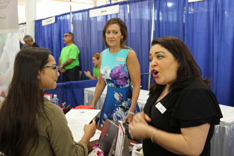 In this March 28, 2018, photo, Roxy Creed, left, speaks to Mandara Spa Operations Manager Lena Andrade about employment opportunities at a job fair in Honolulu. Recently released numbers show Hawaii boasts the United States' lowest jobless rate, at 2.1 percent. But experts say the figure is masking underlying problems.