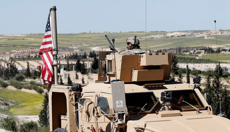 A U.S. soldier sits on an armored vehicle on a road leading to the tense front line with Turkish-backed fighters, in Manbij, north Syria.