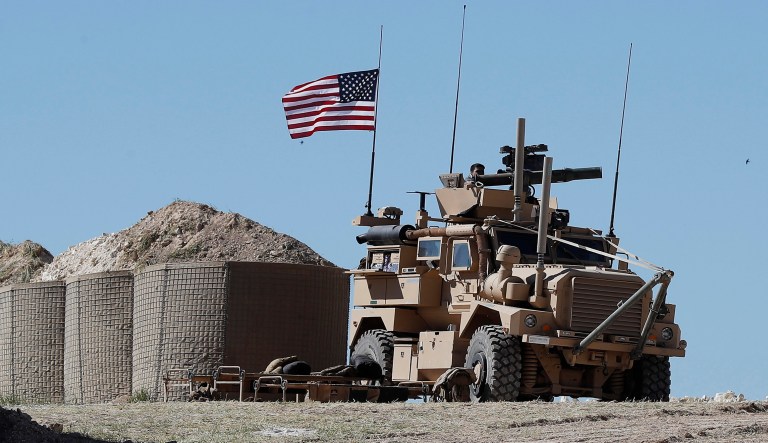 A U.S. soldier sits on an armored vehicle on a newly installed position, near the tense front line between the U.S-backed Syrian Manbij Military Council and the Turkish-backed fighters, in Manbij, north Syria, Wednesday, April 4, 2018. A week ago, there was just a single house where U.S. soldiers had hoisted a U.S. flag on a hill a little ways back from a tense front line in Syria. Now on Wednesday stood a growing outpost with a perimeter of large sand barriers and barbed wire, a new watch tower and half a dozen armored vehicles, The Associated Press found.