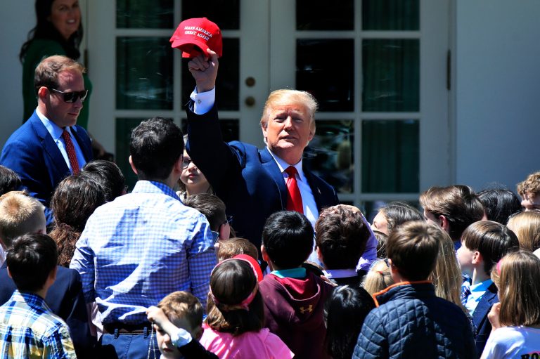 President Donald Trump surrounded by children, waves, a Make America Great Again hat, on the Rose Garden in celebration of "Bring Our Daughters and Sons to Work Day" at the White House in Washington, Thursday, April 26, 2018.