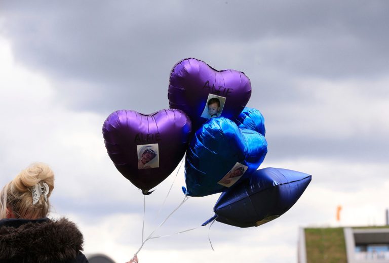 A woman holds balloons with photos of Alfie Evans, outside Alder Hey Children's Hospital, following the death of the 23-month old who was being treated at the hospital, in Liverpool, England on Saturday.