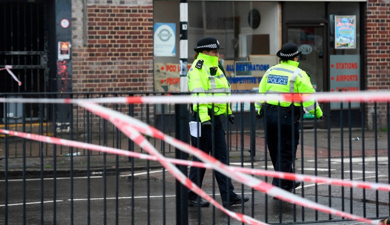 Police officers stand at a cordon in Queensbury, northwest London, on May 2, where a man was shot dead outside Queensbury Tube station.