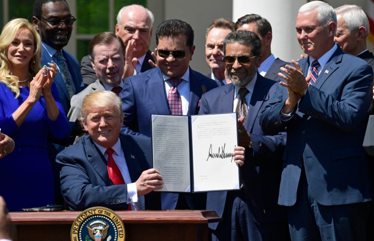 President Trump holds up an executive order that he signed during a National Day of Prayer event in the Rose Garden of the White House in Washington, D.C.