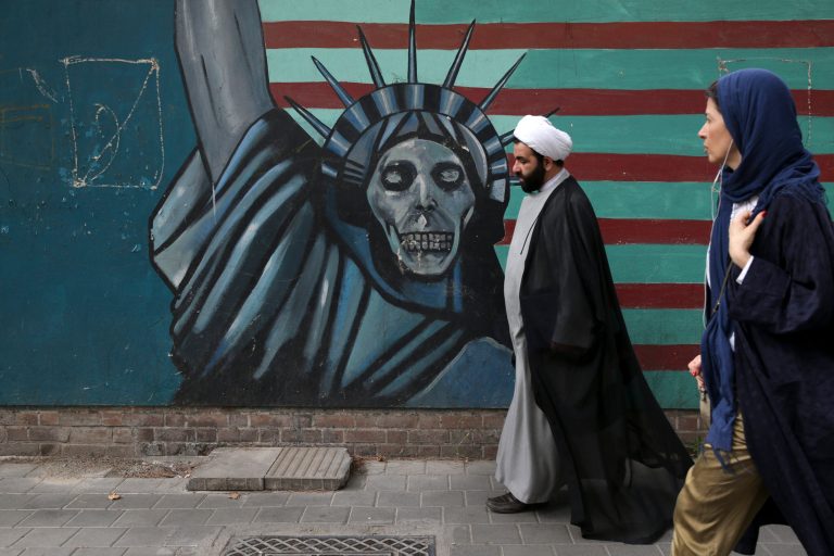 A cleric and a woman walk past an anti-U.S. mural painted on the wall of the former U.S. Embassy in Tehran, Iran, Tuesday, May. 8, 2018. President Donald Trump prepared to tell the world Tuesday whether he plans to follow through on his campaign threat to pull out of the landmark nuclear accord with Iran, as European allies braced for the potential fallout after a last-ditch persuasion effort.