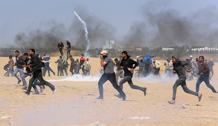 Palestinians run for cover from teargas fired by Israeli troops near the border fence, east of Khan Younis, in the Gaza Strip on Tuesday.