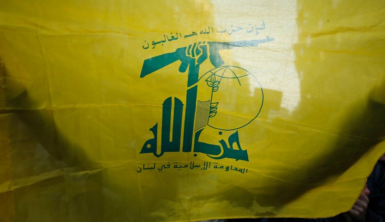 A protester holding a flag of Lebanon's Hezbollah militant group marches during a demonstration.